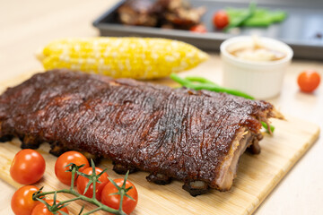 Oven baked BBQ pork ribs with sweet corn, bean and tomato