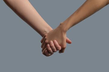 Close-up of light skinned and dark skinned people holding hands