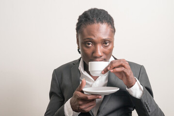 Young handsome African businessman with dreadlocks drinking coffee