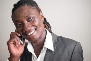 Face of happy young handsome African businessman with dreadlocks talking on the phone