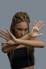 Sad young African American woman making cross with arms, showing palm with stop racism lettering