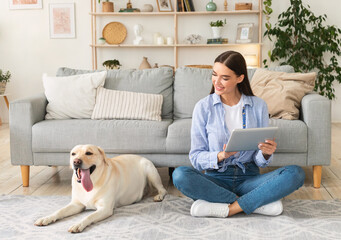 Young woman at home with a tablet and labrador