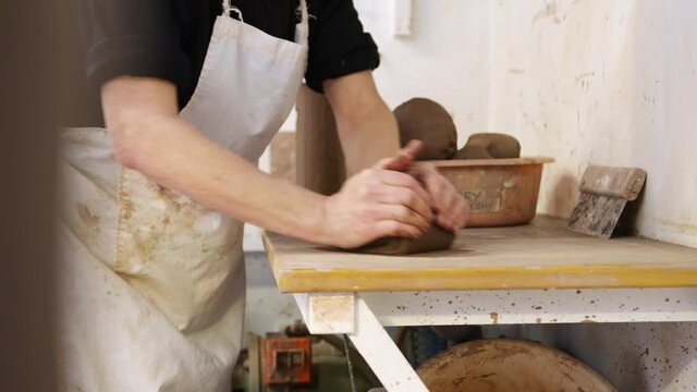 Close up of male potter rolling out lump of clay in ceramics studio - shot in slow motion