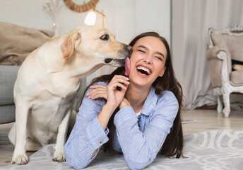 Young smiling woman with dog lying on floor - obrazy, fototapety, plakaty