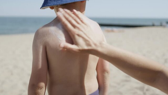 Mother Applying Sunblock Cream on Kid. Mom Applying Sunscreen Lotion on Body Son at Beach. Mother Preparing Child for Bath in Sea. Happy Family at Beach Sun Protection. Travel Summer Suntan Vacation.