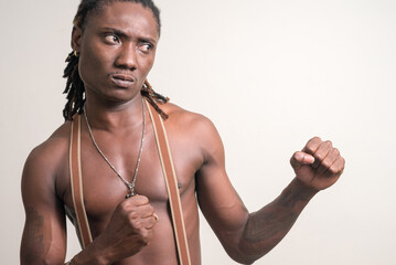 Stressed young muscular African man with dreadlocks ready to fight shirtless