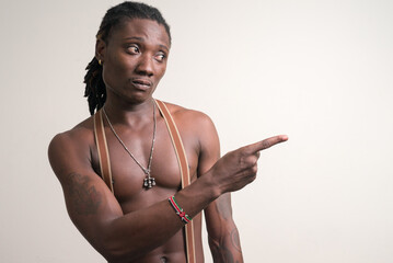 Young handsome muscular African man with dreadlocks pointing finger shirtless