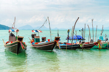 Fototapeta na wymiar Authentic Thai long tail fishing boats docked at Thong Krut beach on a day, Koh Samui, Thailand