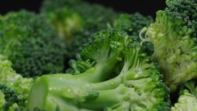 Fresh broccoli pieces on black background, Extreme Closeup Pan Right