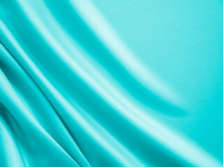 Smooth elegant wavy turquoise silk or satin luxury cloth fabric texture, abstract background design.
