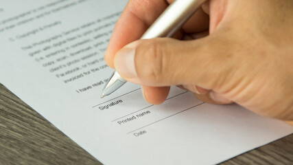 A hand of a man signing a document. Hand holding a pen. 