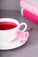 Fototapeta na wymiar Raspberry tea, pink freesia flowers and books on a gray background