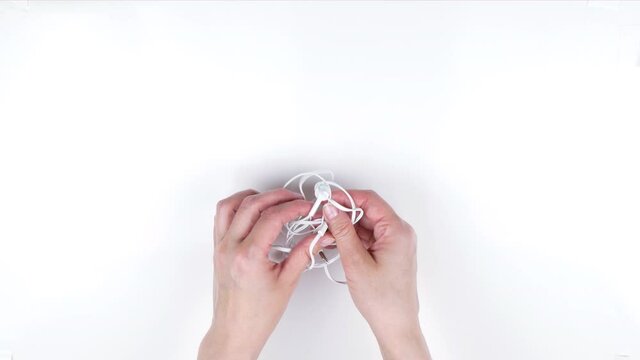 Woman trying to untangle earbuds or headphones.