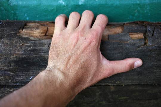 The male hand holds the old wooden board tightly.