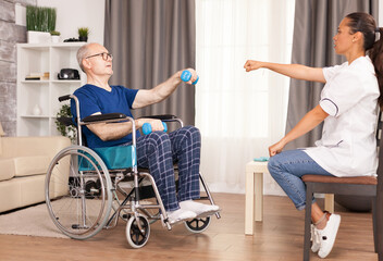 Man in wheelchair exercising with dumbbell for recovery. Disabled disability old person with...