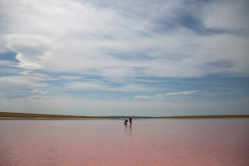 Young couple with the baby carriage at pink salt Lake Kobeituz in north Kazakhstan's Akmola Region.