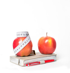 Диета. Dieting. Diet. Red Apples tied with diet measuring tape, stands on a notepad in front of a mirror. Female body types. Composition isolated on white background. Red apple. 90/60/90