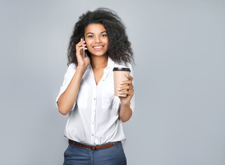 Portrait of a beautiful african girl with coffee and phone in hand