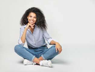 Portrait of a beautiful african woman sitting on gray background