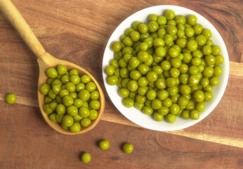 Marinated green peas. Peas. Canned green peas in plate. Green peas in a wooden spoon macro shot.  Зеленый горошек. 