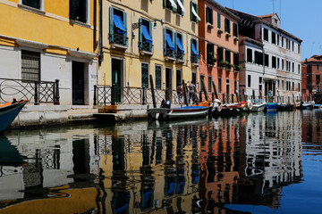 Fototapeta na wymiar Reflections of colourful houses and boats in Venice