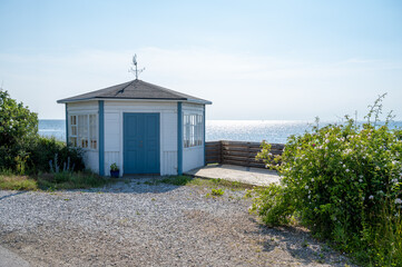 An old gazebo painted white and blue stands by the ocean in the small fishing village Barsebäckshamn in southern Sweden