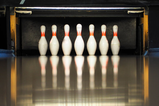 seven white bowling pins before the strike . Hobbies and recreation . play bowling