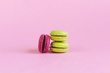 Tasty french light green and pink macaroons on a pink pastel background.