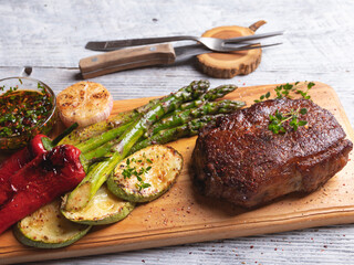 juicy roasted steak with asparagus, pepper, zucchini, sauce on a cutting board close-up