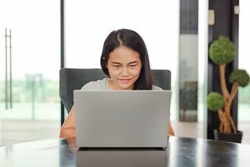 Portrait asian woman using laptop computer working on the table at home. People during the...
