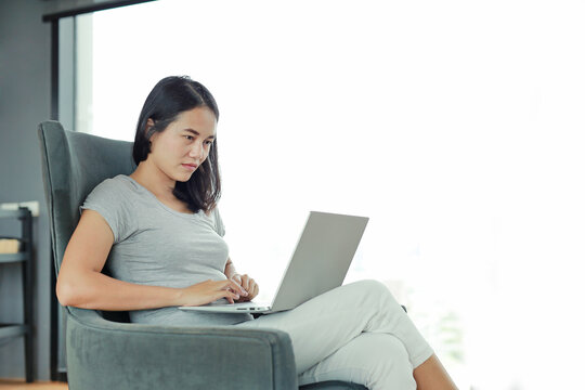 Portrait asian woman using laptop computer working on the table at home. People during the introvert time at home from the epidemic