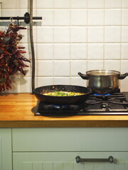 Healthy summer natural food. Fried eggs with tomatoes, tomatoes and herbs in a black pan on the stove.