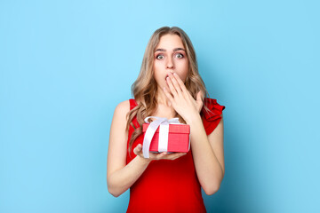 Beautiful woman holding gift on blue background