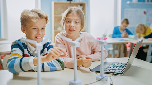 Schoolgirl and Schoolboy Work with Wind Turbine Prototype, Learning about Environment and Renewable Energy . Elementary School Science Classroom with Children Working on Technology. STEM Education - Powered by Adobe