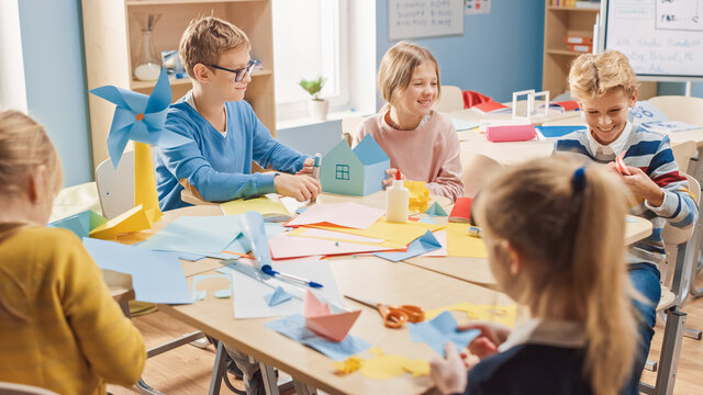 Elementary School Arts & Crafts Class: Diverse Group of Smart Children Have Fun on a Handicraft Project, Using Colorful Paper, Scissors and Glue to Create Fun Papier Mache.
