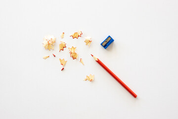 Back to school concept. Red pencil with sharpener and wood shavings on a white table. Flat lay