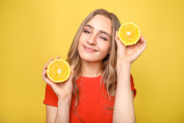 Beautiful woman holding oranges in hands on yellow background