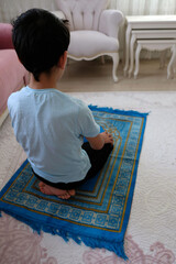 Fototapeta na wymiar a boy performing a prayer, a muslim performing a prayer on a prayer rug,