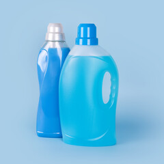 Bottles of detergent and fabric softener on blue background. Containers of cleaning products, household chemicals. Liquid laundry detergent and conditioner. Laundry day, washing and cleaning concept.