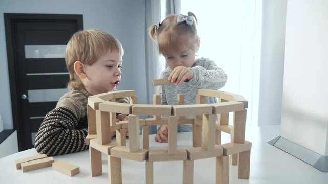 play in designer wooden sticks teamwork. happy family kids little boy a and girl play in wooden blocks lifestyle cubes build house. children brother and sister collect designer development of fine