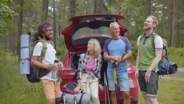 Happy family on trip together standing near open car trunk