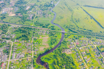 Aerial view landscape of winding small river among the small town railway station and bridge, stream in green field, top view meadow.