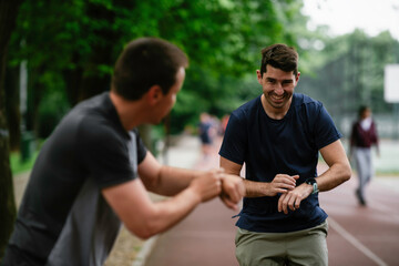 Young men training on a race track. Two young friends running on the athletics track