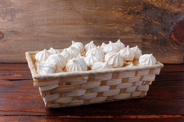 Fototapeta na wymiar sigh or meringue is a sweet made from egg whites, sugar and lemon in the basket on wooden table