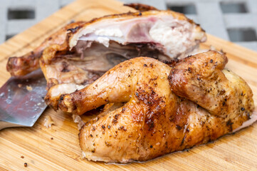 A Barbecued Cornish Hen Cut in Half and Sitting on a Bamboo Cutting Board