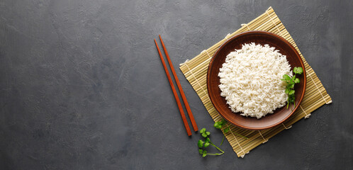 Boiled rice, chopsticks and bamboo napkin on a gray concrete background. Asian food. Top view with...