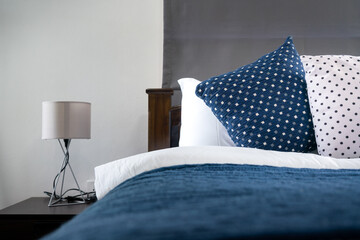 Bedroom in contemporary style with blue and white bedding set, interior object photo. Selected focus at the pillow object.