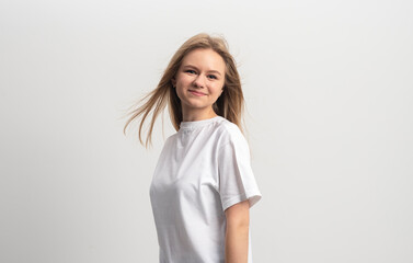 Close-up alluring happy smiling blonde young woman in white t-shirt turn sideways looking forward...