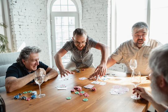 Always Young. Group Of Happy Mature Friends Playing Cards And Drinking Wine. Look Delighted, Excited. Caucasian Men Gambling At Home. Sincere Emotions, Wellbeing, Facial Expression Concept.