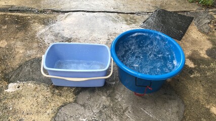 Blue tank has a lot of water in a rainy day,on cement floor,while it rains,we can take can bring...